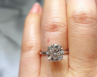 May include: A silver ring with a large, round, clear diamond. The ring is on a person's finger. The text "forever for love" is written on the finger.