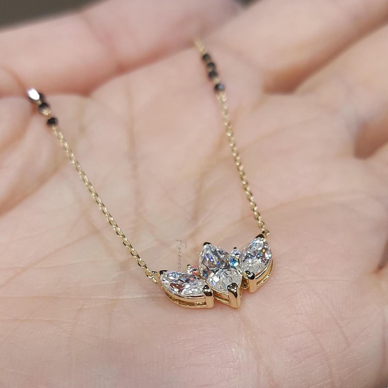 May include: A gold chain necklace with a pendant featuring three marquise-shaped diamonds set in a gold setting.