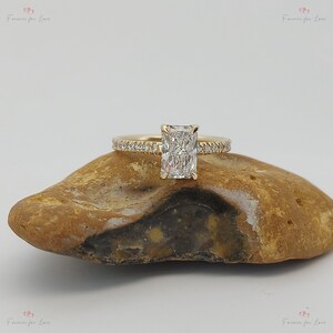 May include: A gold engagement ring with a rectangular diamond and a band of small diamonds.