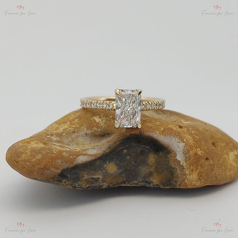 May include: A gold engagement ring with a rectangular diamond and a band of small diamonds.
