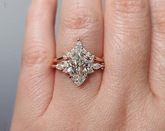 May include: A rose gold ring set featuring a central marquise-cut diamond surrounded by a cluster of smaller round and marquise-cut diamonds. The design includes a matching curved band that frames the main stone, creating a layered look.