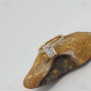 May include: A gold engagement ring with a radiant cut diamond and a pave diamond band.