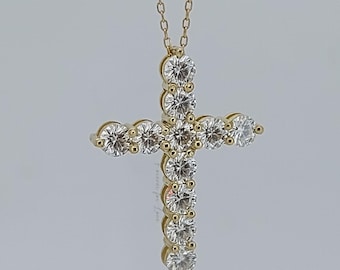Könnte beinhalten: Eine goldfarbene Kreuz-Anhänger-Halskette mit einer zarten Kette. Das Kreuz ist mit mehreren runden, klaren Edelsteinen besetzt. Die Halskette wird vor einem hellgrauen Hintergrund präsentiert.