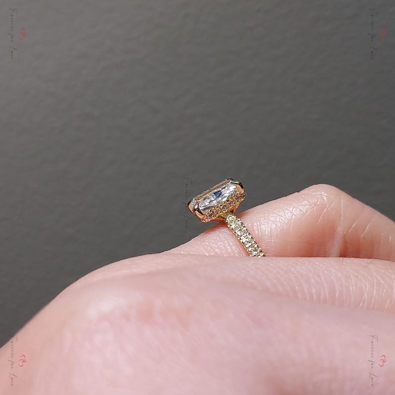 May include: A gold engagement ring with a large, clear, cushion-cut diamond center stone and a pave diamond band.