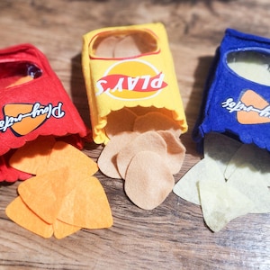 May include: Three felt bags filled with felt chips. The bags are yellow, red, and blue. The bags have the text "Play-Doh" on them. The chips are different colors.
