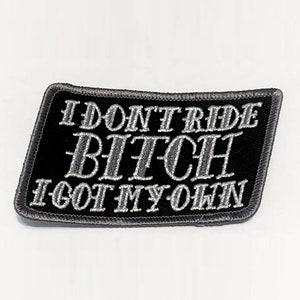 May include: Black rectangular patch with grey embroidered text: "I DON'T RIDE BITCH I GOT MY OWN". The patch has a grey border and is set against a white background. The text is in a bold, stylized font.