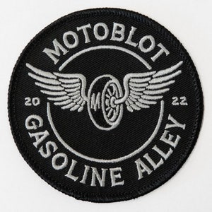 May include: A black and silver embroidered patch with the text "MotoBlot Gasoline Alley 20 22" and a winged wheel design.