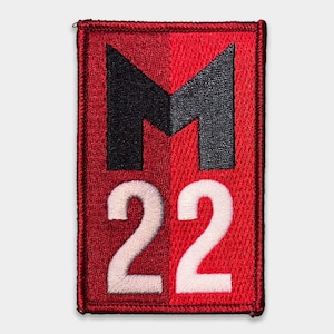 May include: Red and black embroidered patch with a stylised letter "M" and the number "22" in white.