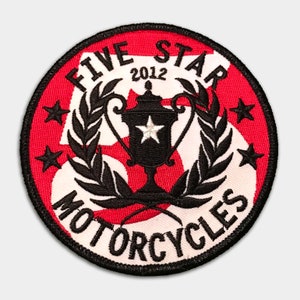 Puede incluir: Un parche bordado rojo y blanco con el texto "Five Star Motorcycles" y un trofeo con una estrella en la parte superior. El texto "2012" también está incluido en el parche.