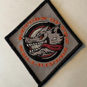 May include: A gray embroidered patch with a black border. The patch features a snarling wolf's head with red eyes and a red tongue. The text "RETURN OF THE SOUL RIDERS" is embroidered in orange around the wolf's head.