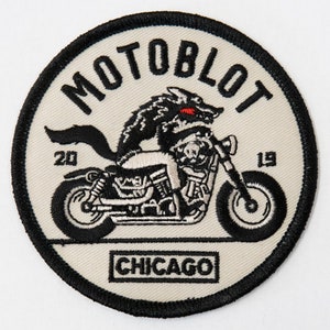 Puede incluir: Un parche bordado en blanco y negro con un lobo montando una motocicleta. El parche dice "MOTOBLOT" y "CHICAGO" y tiene los números "20" y "19" a cada lado de la motocicleta.
