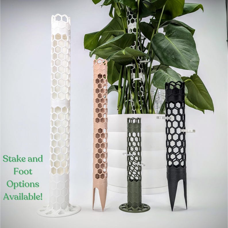 May include: Four plant stakes made of a honeycomb-like material in white, pink, green, and black. The stakes are designed to support climbing plants. The text "Stake and Foot Options Available!" is visible in the image.