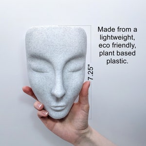 May include: A white face-shaped planter made from lightweight, eco-friendly, plant-based plastic. The planter is 7.25 inches tall.