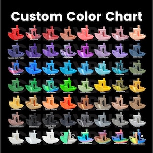 May include: A colour chart displaying a range of filament colours for 3D printing. The colours are shown on small, boat-shaped objects. The chart includes colours such as red, blue, green, yellow, orange, purple, black, white, and more.