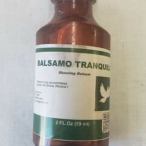 May include: A brown glass bottle with a white cap labelled "Balsamo Tranquilo Shooting Balsam" with a green label and a white dove graphic. The bottle contains 2 fl oz (59 ml) of liquid.