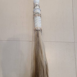 May include: A white horsehair tail with a white and beige decorative handle. The handle is adorned with rhinestones, lace, and shells.