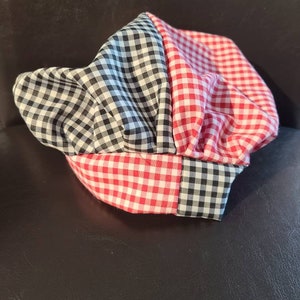 May include: A red and black checkered chef's hat. The hat is made of fabric and has a rounded shape.