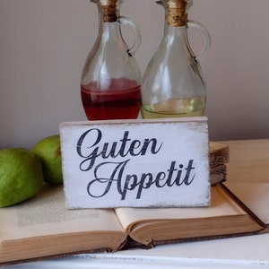 German home decor sign for kitchen. Guten Appetit wood sign. pear sitting on vintage book, vintage oil & vinegar decanter