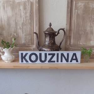 Kouzina Greek Kitchen sign. Silver teapot, white creamer with plants