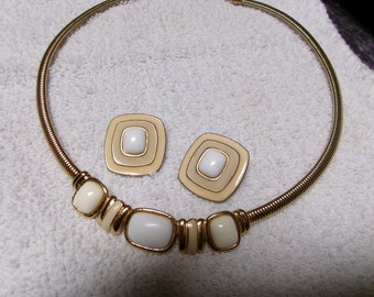 May include: A gold tone choker necklace with white and cream colored oval and square shaped beads. Matching earrings with white and cream colored square shaped stones.