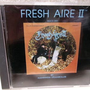 May include: A CD case with a black background and a colorful image of a band in a forest setting. The title of the album is "Fresh Aire II" by "Mannheim Steamroller" and the album number is "AGCD 359".