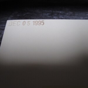 May include: A close-up of a white card with the date "DEC 05 1995" printed in brown ink.