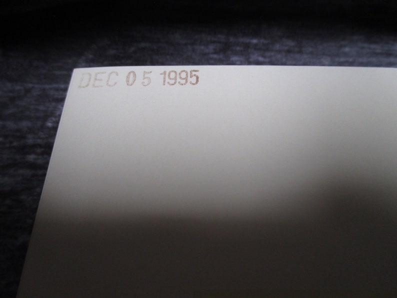 May include: A close-up of a white card with the date "DEC 05 1995" printed in brown ink.