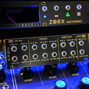 May include: A black synthesizer module with knobs and jacks. The module is labelled "ZORX" and has various inputs and outputs, including "ARP/SEQ", "KEYBOARD", "STEREO DELAY", and "AUDIO".