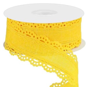 May include: A spool of bright yellow ribbon with a scalloped edge and decorative cut-out details. The ribbon is unrolled, revealing its texture and design. Perfect for crafts and gift wrapping.
