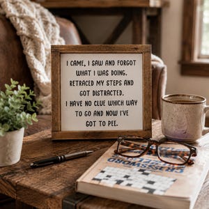 May include: A square wooden sign with a dark brown frame and a white background featuring the black text: I CAME, I SAW AND FORGOT WHAT I WAS DOING. RETRACED MY STEPS AND GOT DISTRACTED. I HAVE NO CLUE WHICH WAY TO GO AND NOW I'VE GOT TO PEE.