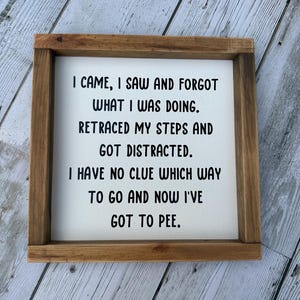 May include: A square wooden sign with a dark brown frame and a white center panel. The text in black reads: I CAME, I SAW AND FORGOT WHAT I WAS DOING. RETRACED MY STEPS AND GOT DISTRACTED. I HAVE NO CLUE WHICH WAY TO GO AND NOW I'VE GOT TO PEE.