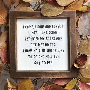 May include: A square wooden sign with a dark brown frame and a white center featuring black text that reads: I CAME, I SAW AND FORGOT WHAT I WAS DOING. RETRACED MY STEPS AND GOT DISTRACTED. I HAVE NO CLUE WHICH WAY TO GO AND NOW I'VE GOT TO PEE.