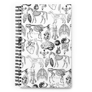 Puede incluir: Un cuaderno de espiral con un patrón repetido de ilustraciones anatómicas en blanco y negro de esqueletos y órganos de animales. El cuaderno tiene un fondo blanco y una encuadernación en espiral negra.