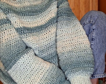 May include: A soft, crocheted sweater with a light blue, green, and white ombre color pattern. The sweater has a relaxed fit and long sleeves.