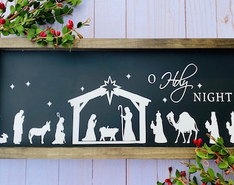 May include: A black framed wooden sign with a white silhouette of the nativity scene and the text "O Holy Night".
