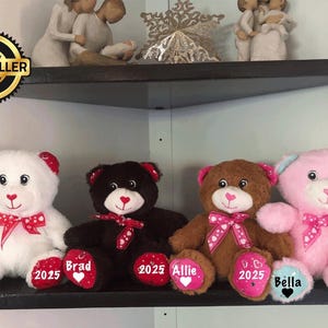May include: Four plush teddy bears with red and white polka dot bows and hearts. The bears are white, brown, black, and pink. Each bear has a personalized name tag with the year 2025.