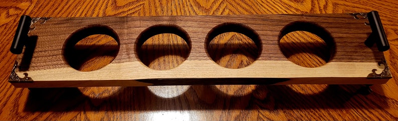Pu&ograve; includere: Un vassoio in legno con quattro tagli circolari, perfetto per contenere bicchieri o tazze. Il vassoio &egrave; realizzato in due tipi di legno, uno chiaro e uno scuro, e ha accenti metallici decorativi alle estremit&agrave;.