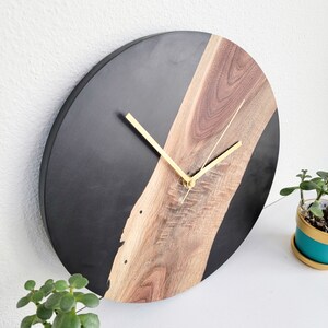 May include: A black and brown resin clock with gold hands. The clock face is half black and half brown wood.