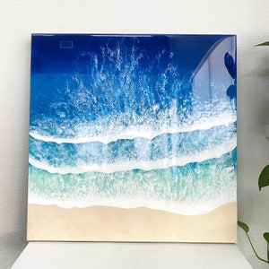 May include: Abstract painting of ocean waves with blue, white, and green colors. The painting depicts a seascape with foamy waves crashing on a sandy beach.
