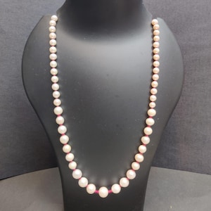 Puede incluir: Una taza de cerámica blanca con un asa negra y el texto "But First, Coffee" en negrita negra. La taza se encuentra sobre un fondo borroso, resaltando su diseño limpio.