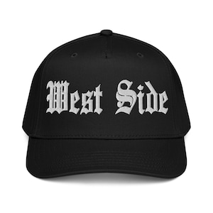 Op de afbeelding: Zwarte baseballcap met de geborduurde tekst "West Side" in witte gotische letters. De cap heeft een gebogen klep en een gestructureerde pasvorm.