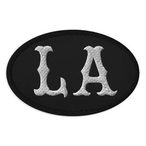 May include: Black oval patch with white embroidered letters "LA" in a stylized font.