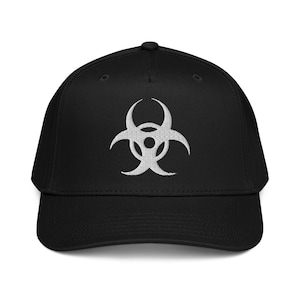 May include: Black baseball cap with a white biohazard symbol embroidered on the front. The cap has a curved brim and a structured fit. The biohazard symbol is centered on the front of the cap.