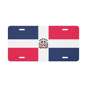 Può includere: Targa rettangolare con la bandiera della Repubblica Dominicana. Il design include una croce bianca che divide la targa in quattro sezioni: blu, rosso, bianco e rosso. Uno stemma è centrato sulla sezione bianca.