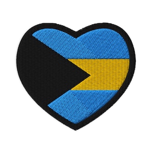 May include: Embroidered heart-shaped patch featuring the flag of The Bahamas. The design includes a black triangle, a yellow chevron, and blue stripes. The patch has a black border and is likely for clothing or accessories.