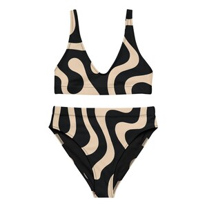 May include: A two-piece swimsuit set featuring a black and tan wavy pattern. The top has a V-neck design with thick straps, and the high-waisted bottoms offer full coverage. The swimwear is made of a smooth, likely stretchy material.