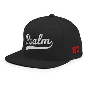May include: Black baseball cap featuring the word "Psalm" in white script embroidery. The number "27" is embroidered in red on the side. The cap has a flat peak.