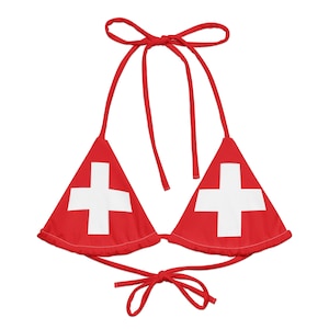 Könnte beinhalten: Rotes Bikini-Oberteil mit weißem Kreuz-Design, mit Bindebändern am Hals und am Rücken. Die Dreiecks-Cups zeigen die Schweizer Flagge. Ein Sommer-Bademodenartikel.