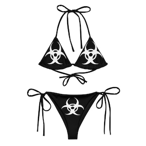 May include: Black bikini with a white biohazard symbol print. The top is a triangle style with adjustable straps. The bottom is a cheeky style with ties on the sides.
