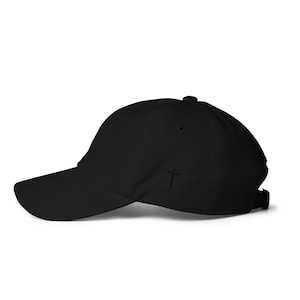 May include: A black baseball cap with a small cross embroidered on the front.